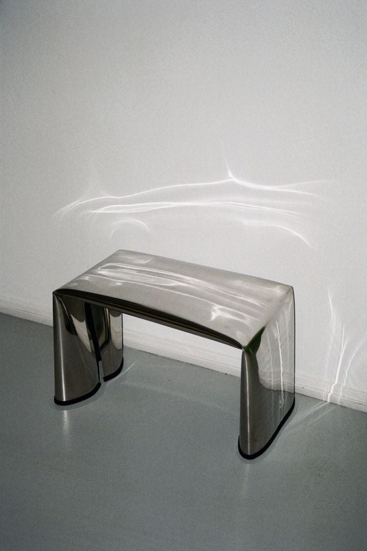 A minimalist silver table styled in a neutral room, part of the Multiaire brand world focused on intentional design and workspace clarity.