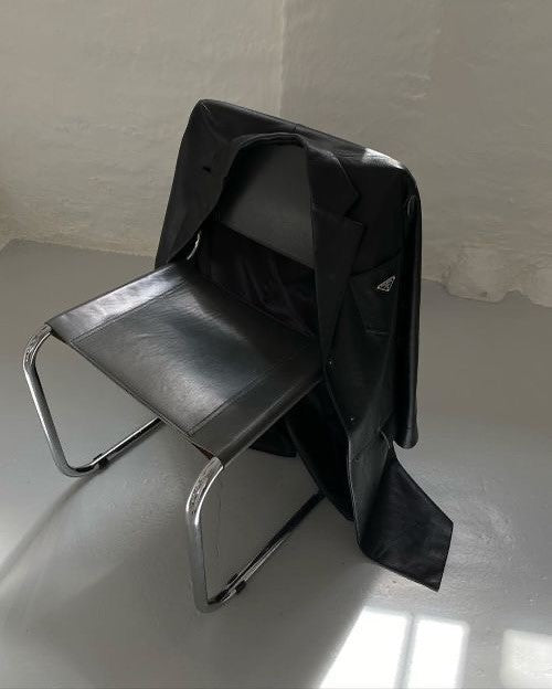 Black leather chair with a black cover draped over it on a white floor.